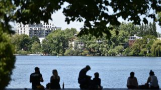 Menschen sitzen am Ufer der Insel der Jugend am Treptower Park in Berlin