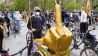Ein Fahrrad-Demonstrant steht mit einer goldenen Skulptur, die den ausgestreckten Mittelfinger zeigt, am Großen Stern (Bild: imago images/Stefan Zeitz)