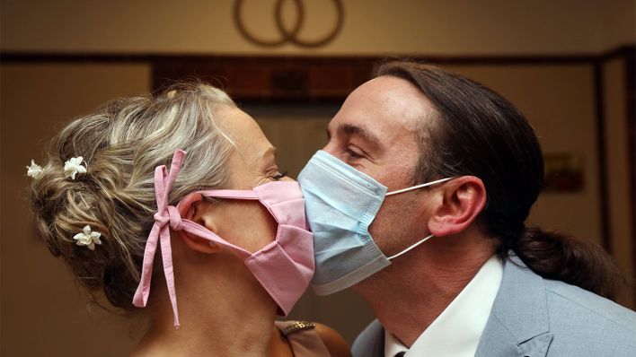 Archivbild: Brautpaar kuesst sich in Zeiten der Coronapandemie mit Mund-Nasen-Schutz. 14.05.2020 (Bild: imago images/Frank Sorge)