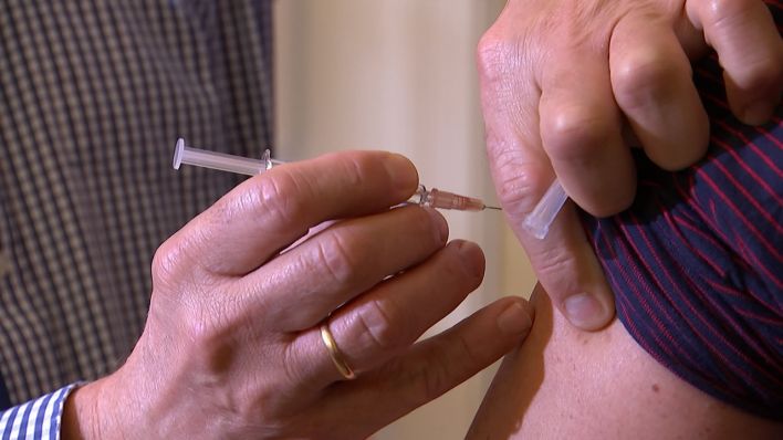Eine Person hält eine Spritze mit Impfstoff in der Hand und impft eine andere Person. (Reporterbild: rbb)