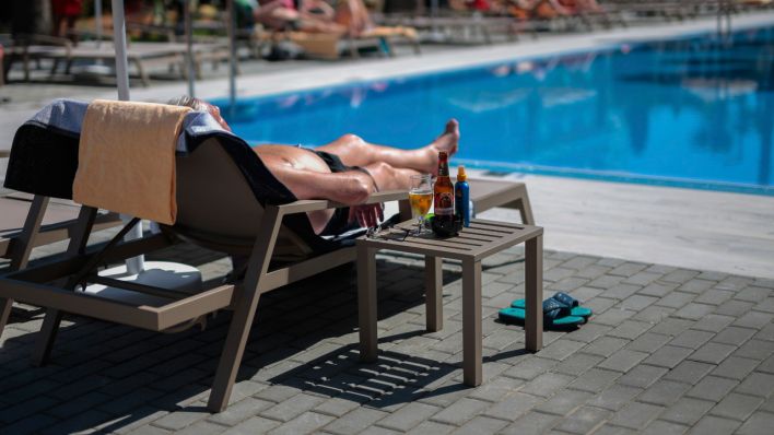 Ein deutscher Tourist sonnt sich am Schwimmbad des Hotels in Berlin (Quelle: dpa/Joan Mateu)
