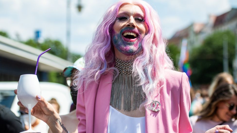 Ein Teilnehmer der "CSD Berlin Pride" trägt rosane Kleidung und einen bunt gefärbten Bart. (Quelle: dpa/Christophe Gateau)