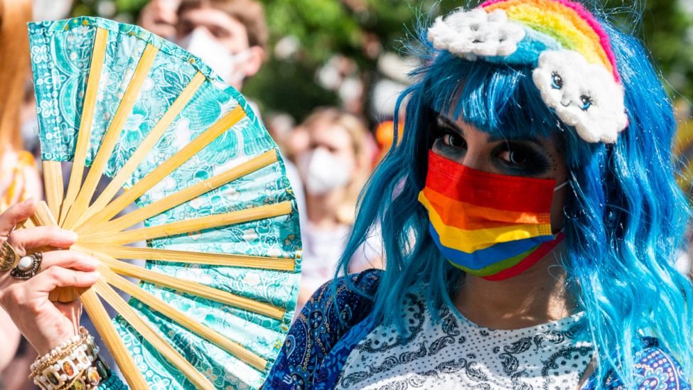 Ein Teilnehmer der "CSD Berlin Pride" trägt einen Regenbogenfarbenen Mund-Nasen-Schutz. (Quelle: dpa/Christophe Gateau)