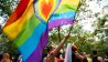 Ein Teilnehmer der "CSD Berlin Pride" trägt eine Regenbogenfarbene Flagge mit einem Herz. (Quelle: dpa/Christophe Gateau)