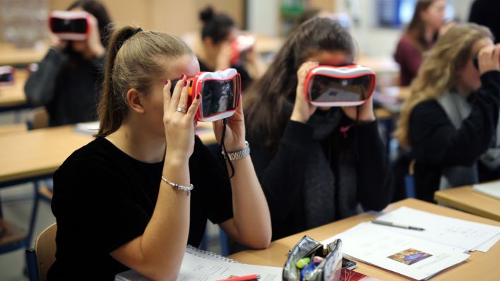 Schüler:innen arbeiten im digitalen Unterricht mit Virtual Reality-Brillen. (Quelle: dpa/Ina Fassbender)
