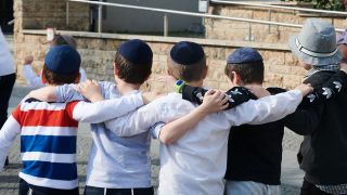 Kinder, die Kippa tragen, haben sich im Arm und tanzen vor dem Bauplatz der zukünftigen Synagoge in Potsdam (Quelle: DPA/Annette Riedl)