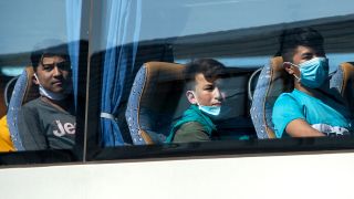 Symbolbild: Junge Flüchtlinge, teilweise mit Mundschutz, sitzen in einem Bus am Flughafen Hannover. (Quelle: dpa/Hauke-Christian Dittrich)