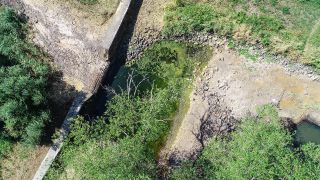 Ausgetrocknet ist das Flussbett der Schwarzen Elster mit zwei kleinen Wasserlöchern (Luftaufnahme mit einer Drohne). (Quelle: dpa/Patrick Pleul)