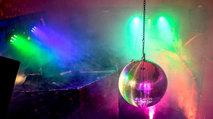 Eine Diskokugel dreht sich in einem Club und reflektiert das einfallende Licht der Scheinwerfer und Lampen. (Quelle: dpa/Britta Pedersen)
