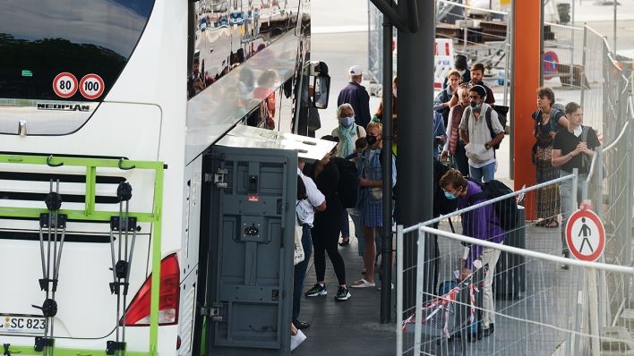 Reisende bringen ihr Gepäck auf dem Zentralen Omnibusbahnhof (ZOB) in den Reisebus. (Quelle: dpa/Annette Riedl)