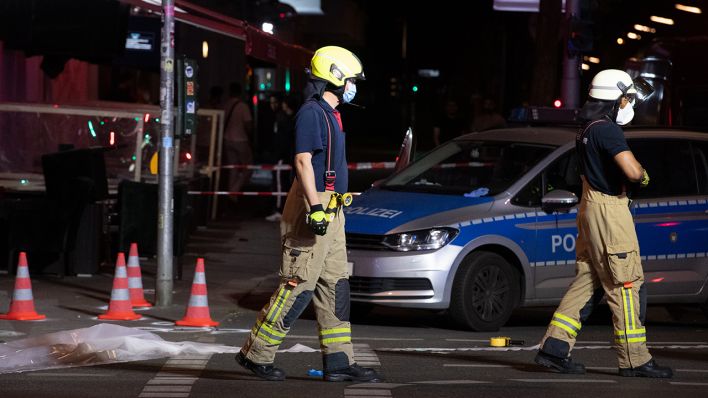 Feuerwehrleute gehen auf der Müllerstraße an Leitkegeln vorbei. In Berlin-Wedding sind am späten Sonntagabend vermutlich mehrere Schüsse gefallen. (Quelle: dpa/Paul Zinken)