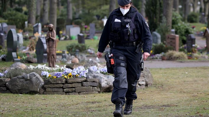 Symbolbild: Eine Polizistin geht über einen Berliner Friedhof. (Quelle: dpa/O. Berg)