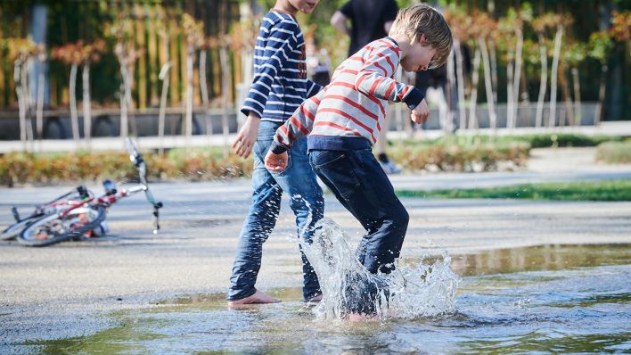 Symbolbild: Zwei Kinder spielen im Wasser eines Springbrunnens im Rosengarten am Treptower Park. (Quelle: dpa/A. Riedl)