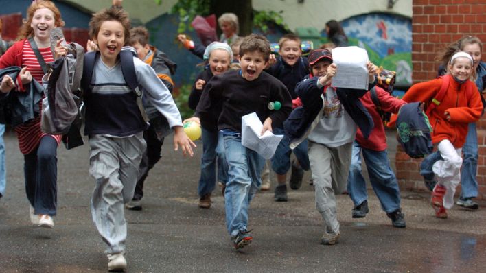 Archivbild: Jubelnd rennen SchülerInnen zum Beginn der Sommerferien über den Schulhof. (Quelle: dpa/K. Nietfeld)
