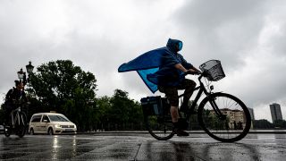 Eine Radfahrerin fährt in Berlin durch den Regen. (Quelle: dpa/F. Sommer)