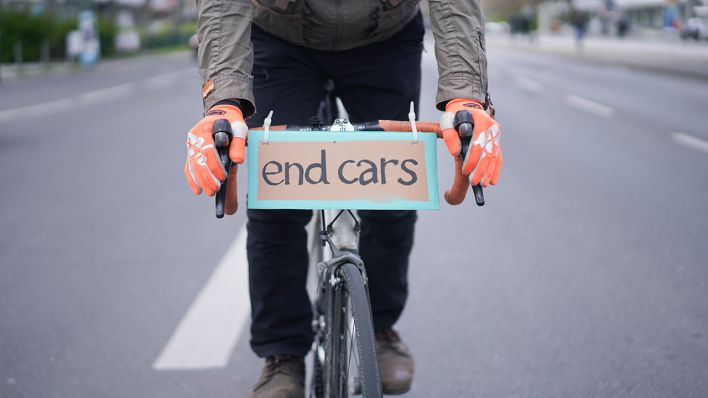 Ein Plakat mit der Aufschrift «end cars» hat ein Teilnehmer einer Demonstration des Volksentscheids «Berlin autofrei» am LEnker seines Fahrrads befestigt. (Quelle: dpa/Jörg Carstensen)