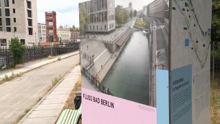 Ein Pappschild zeigt einen Entwurf des Flussbades am in Berlin-Mitte.