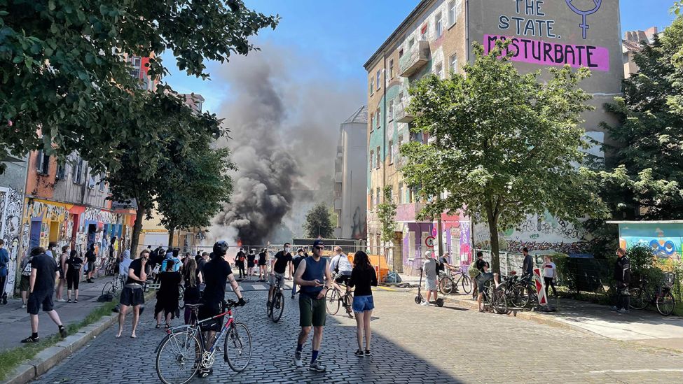 Menschen stehen vor den brennenden Barrikaden auf der Rigaer Straße in Berlin Friedrichshain. (Quelle: rbb)