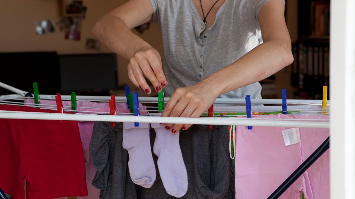 Eine Frau hängt am 31.07.2021 in einer Wohnung in Berlin frisch gewaschene Wäsche auf. (Quelle: dpa/Silvia Marks)