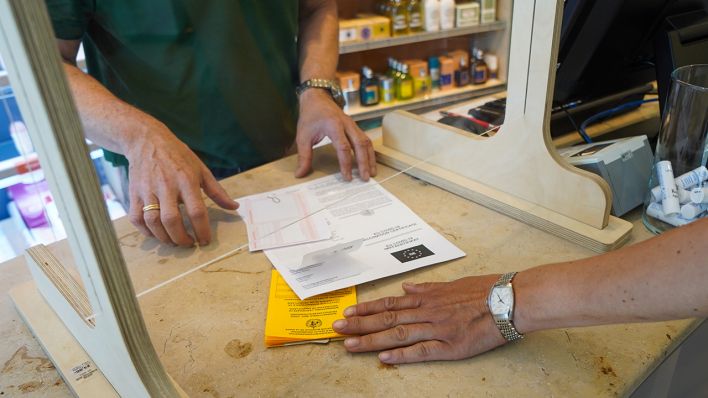 Eine Kundin übergibt am 14.06.2021 ihren Impfpass und ein Covid-19 Impfzertifikat in einer Pankower Apotheke, um sich einen digitalen Impfnachweis ausstellen zu lassen. (Quelle: dpa/Jörg Carstensen)