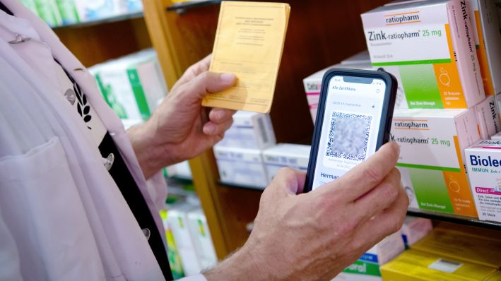 Ein Apotheker hält einen Impfpass und einen digitalen Impfnachweis in den Händen. (Quelle: dpa/Sven Hoppe)