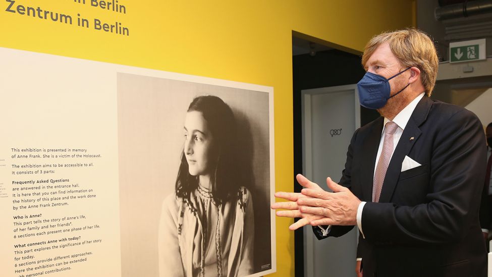 König Willem-Alexander der Niederlande desinfiziert sich am 05.07.2021 vor seinem Besuch der Ausstellung im Anne-Frank-Zentrum die Hände. Er betrachtet dabei eine Informationstafel zum Leben von Anne Frank. (Quelle: dpa/Adam Berry)