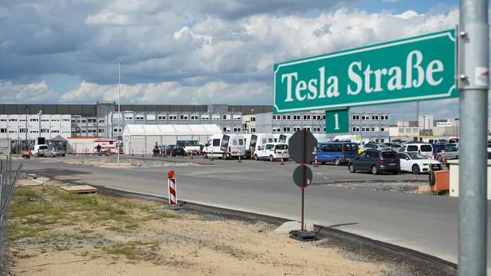 Das Straßenschild "Tesla Straße 1" steht an der Zufahrt zum Baugelände der Tesla Fabrik. (Quelle: dpa/Jörg Carstensen)