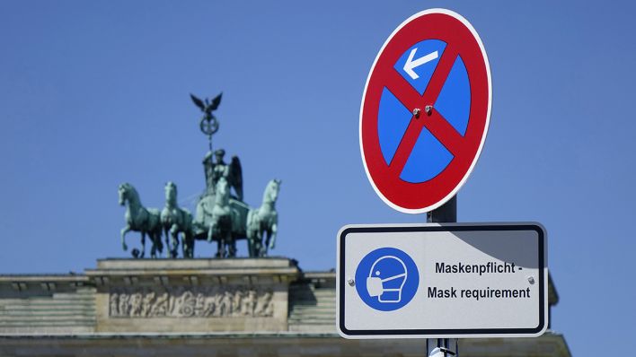 Vor dem Brandenburger Tor mit der Quadriga steht ein Schild mit Maskenpflicht. (Quelle: dpa/Sascha Steinach)