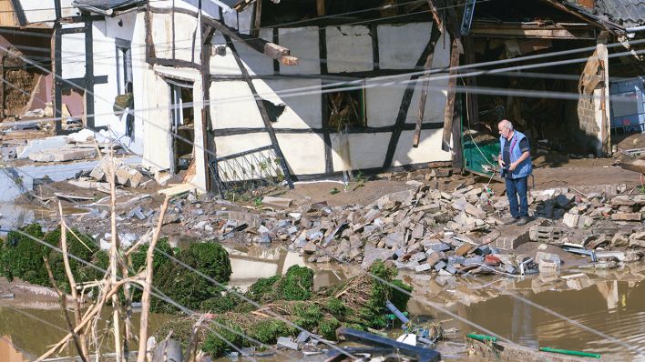 Ein Mann steht neben einem zerstörten Fachwerkhaus im Schutt in dem Ort im Kreis Ahrweiler am Tag nach dem Unwetter mit Hochwasser. (Quelle: dpa/Thomas Frey)