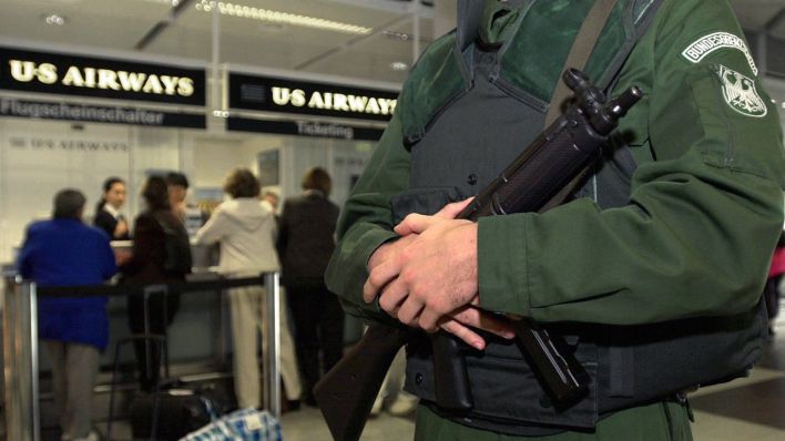 Ein Beamter des Bundesgrenzschutzes steht am 13.9.2001 mit seiner Waffe vor dem Schalter einer amerikanischen Fluggesellschaft auf dem Flughafen. (Quelle: dpa/Matthias Schrader)