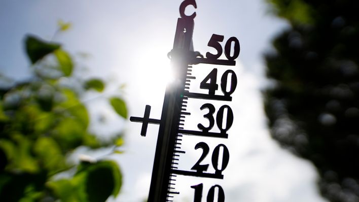 Symbolbild: Ein Thermometer vor der blendenden Sonne in der freien Natur zeigt sommerliche Temperaturen über 30 Grad Celsius an. (Quelle: dpa/Geisler)