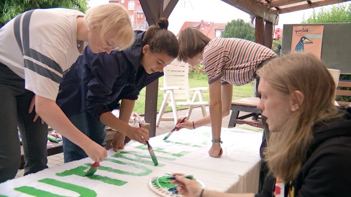 Emma Kiehm (2.v.l.) malt zusammen mit anderen Jugendlichen an einem Banner für eine "Fridays for Future"-Aktion in Neuruppin. (Quelle: rbb/Brandenburg aktuell)