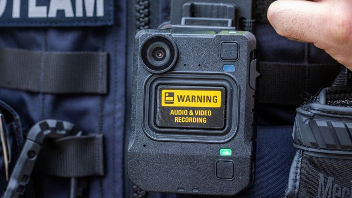 Eine neue Bodycam hängt an der Schutzweste einer Polizeibeamtin. (Quelle: dpa/Jens Büttner)