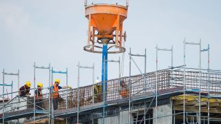 Symbolbild: Bauarbeiter arbeiten auf der höchsten Ebene einer Gebäude-Baustelle. (Quelle: dpa/C. Gateau)