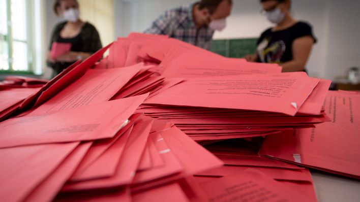 Symbolbild: Wahlhelfer und Wahlhelferinnen öffnen im Klassenzimmer einer Schule die Umschläge der Briefwahl. (Quelle: dpa/H. Schmidt)