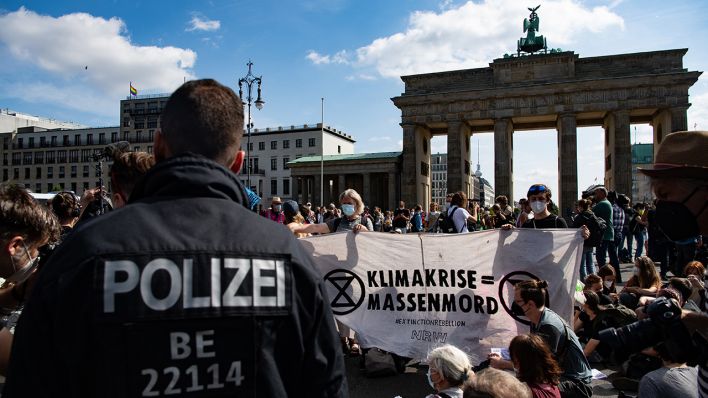 Aktivisten, darunter die Umweltschutzgruppe Extinction Rebellion, protestieren mit einer Sitzblockade auf der Straße am Brandenburger Tor gegen die Umweltpolitik der Regierung. (Quelle: dpa/P. Zinken)