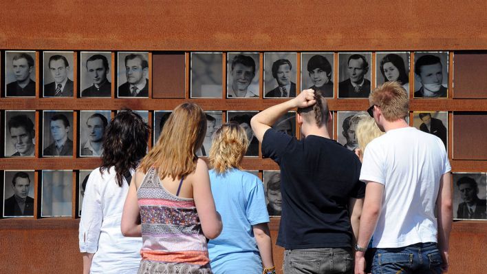 Touristen besichtigen die neu gestaltete Fotowand mit Bildern der bekannten Maueropfer in der Gedenkstätte Berliner Mauer an der Bernauer Straße in Berlin, aufgenommen am 21.04.2011. (Quelle: dpa/Jens Kalaene)