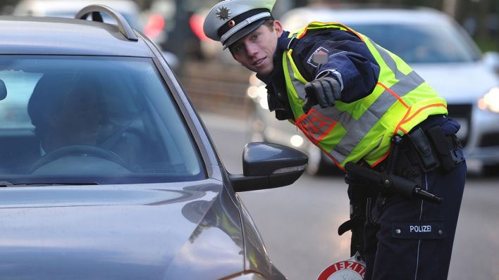 Symbolbild: Ein Polizist fordert einen Wagen zum Parken am Straßenrand auf. (Quelle: dpa/J. Strobel)