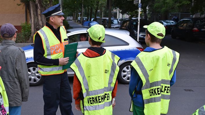 Archivbild: Ein Polizist unterstützt in Berlin Schüler, die als Verkehrshelfer vor einer Schule eingesetzt sind. (Quelle: dpa/J. Kalaene)