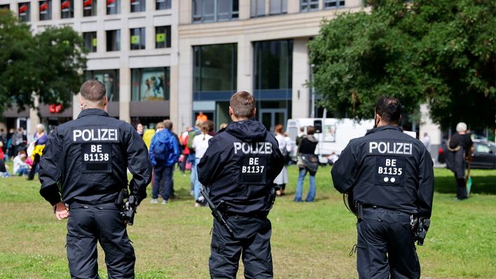 Mehrere Polizisten stehen am 29.08.2021 vor einer Gruppe an Demonstrierenden (Bild: dpa/Jean MW/Geisler-Fotopress)