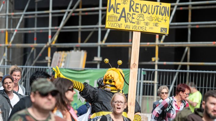 Eine Tafel mit der Aufschrift „We Are Revolution“ trägt ein Teilnehmer einer Demonstration gegen die Corona-Politik am 29.08.2021 (Bild: dpa/Christophe Gateau)