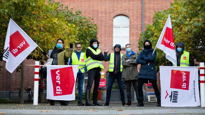 Archivbild: Teilnehmer eines Warnstreiks von Beschäftigten der Berliner Charite stehen auf dem Campus Charite Mitte mit Verdi-Fahnen für ein Foto zusammen. (Quelle: dpa/C. Soeder)