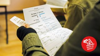 Eine Frau haelt den Stimmzettel fuer die Bundestagswahl in einem Wahllokal (Bild: imago images/Emmanuele Contini/Colourbox)
