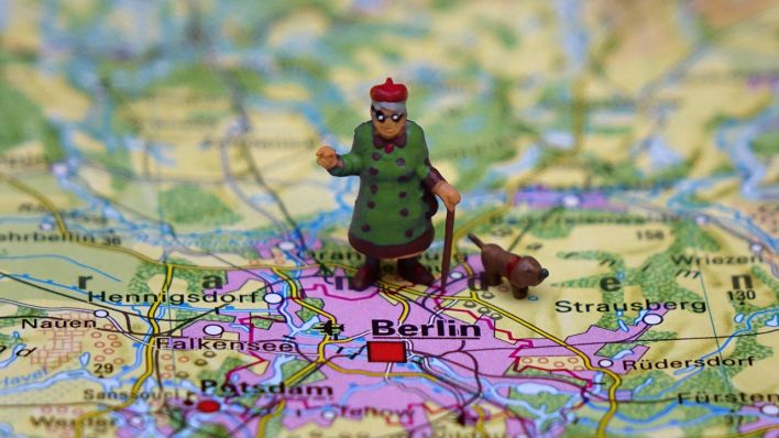 Auf einer Karte mit Berlin und Umgebung steht die Figur einer Seniorin mit Dackel. (Quelle: imago-images/Sascha Steinach)