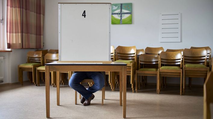 Ein Mann sitzt in einer Wahlkabine. (Quelle: imago-images/Sascha Ditscher)