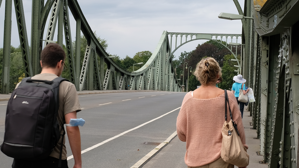 Eine Frau zeigt am 09.08.2021 einem jungen Mann die Glienicker Brücke. (Quelle: rbb|24/Caroline Winkler)