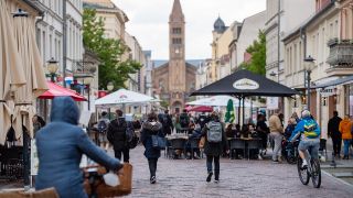 Symbolbild: Menschen gehen im Holländischen Viertel spazieren und sitzen in den Außenbereichen von Cafés und Restaurants. (Quelle: dpa/C. Gateau)