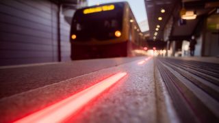 Eine LED-Bahnsteigbegrenzung leuchtet bei einem Test am Bahnhof Berlin-Südkreuz an einem S-Bahnsteig rot, als ein Zug einfährt. (Quelle: Christoph Soeder/dpa)