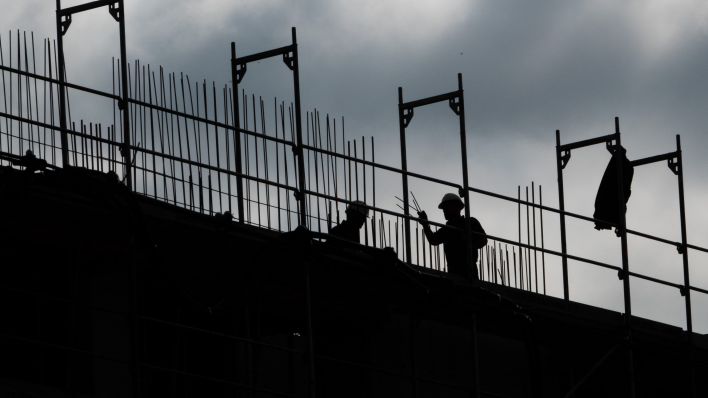 Bauarbeiter stehen auf dem Neubau eines Mehrfamilienhauses. (Quelle: Demy Becker/dpa)