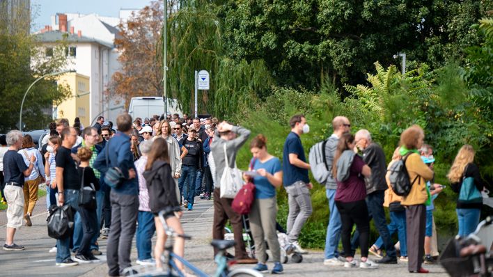 Zahlreiche Menschen stehen in einer langen Schlange vor den Wahllokalen im Tiergarten Gymnasium (Quelle: dpa/Monika Skolimowska)